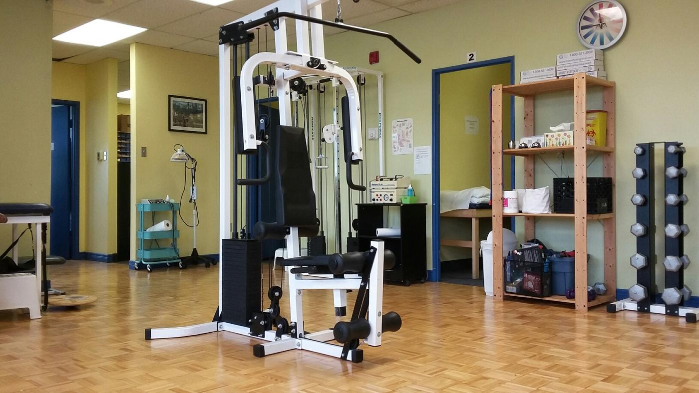 Rehab gym with weight machine and dumbbells, and the door to a private treatment room